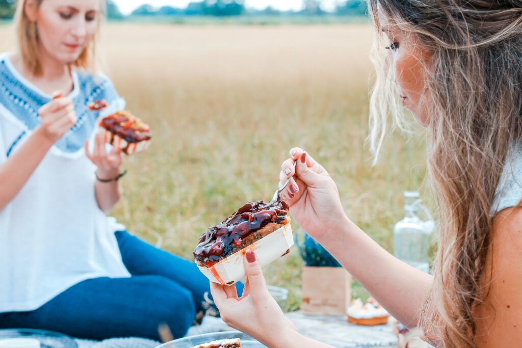 women at a picnic eating dessert how to plan a company picnic
