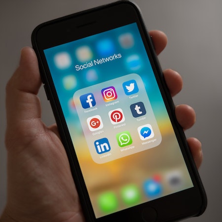 Person Holding Iphone Showing Social Networks Folder - LinkedIn Job Posting Cost