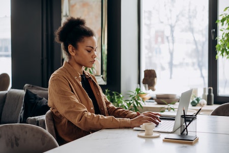 Woman in a Brown Long Sleeve Shirt Typing on Her Laptop -