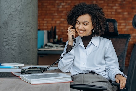 Woman in White Long Sleeve Shirt Sitting on Chair while Talking on Phone - scrum master job description