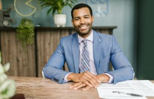 Smiling Man in Blue Suit Sitting by the Table