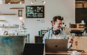 man smiling at his phone while on computer AI Website designer