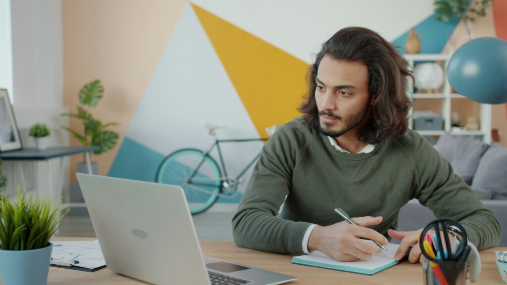 man writing while on laptop client onboarding kit How to Prepare for a Business Audit