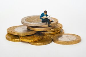 man sitting on a pile of coins money cash index funds for beginners