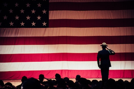 Man Standing On Stage Facing An American Flag - veteran job boards
