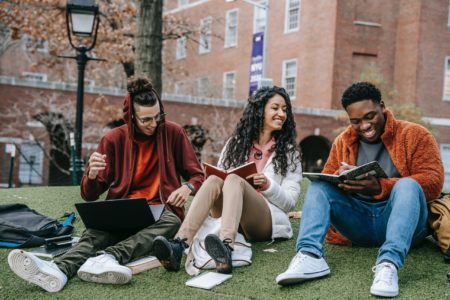 Cheerful students with books sitting near university - Hire College Students