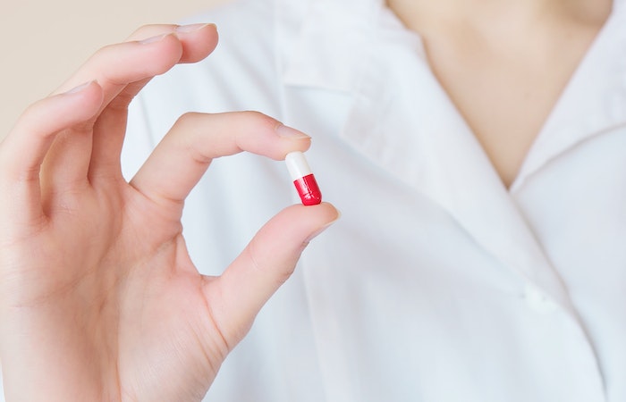 Crop nurse demonstrating small double colored pill - pharmacy tech jobs near me