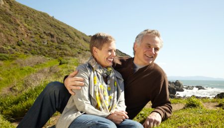 A couple laughs while seated in a beautiful landscape - affordable summer vacations