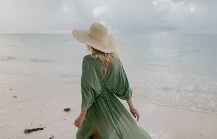 Woman with flying dress standing on wet beach - best places to visit in summer