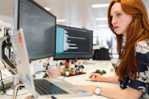 how to manage employee leave featured image red-haired woman at a computer