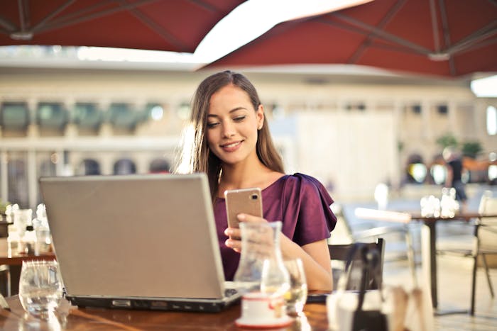 small business month deals featured image woman looking at phone and laptop