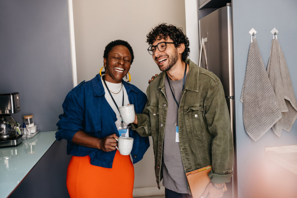 office party ideas Professionals laughing and bonding over coffee in the office breakroom, showing positive workplace culture and teamwork workplace beverages